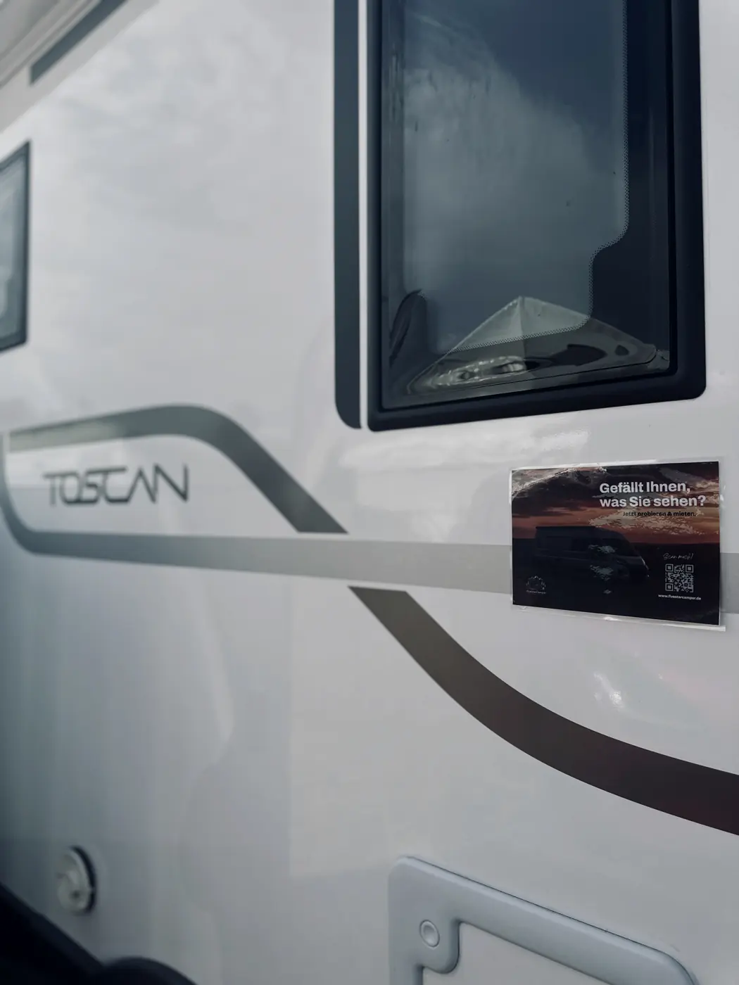 Weißes Reisemobil Toscan mit FiveStarCamper-Aufkleber neben dem Fenster