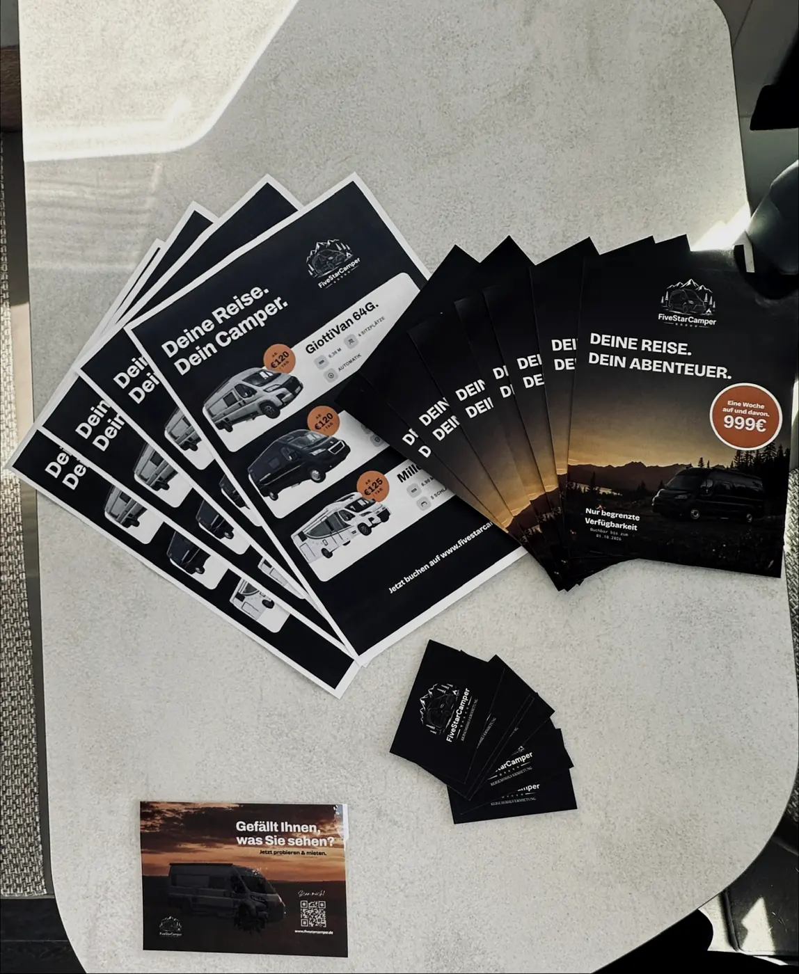 Flyer, Postkarten und Visitenkarten von FiveStarCamper auf einem Campertisch